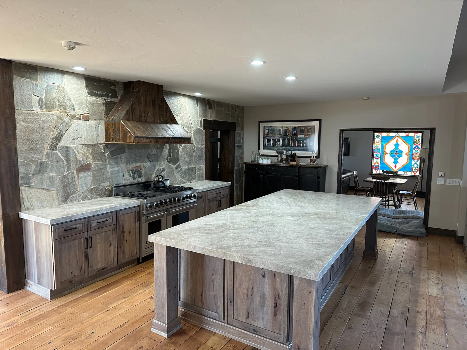 Leathered Taj Mahal quartzite island with a book-matched seam in a Gardnerville kitchen with a stone accent wall