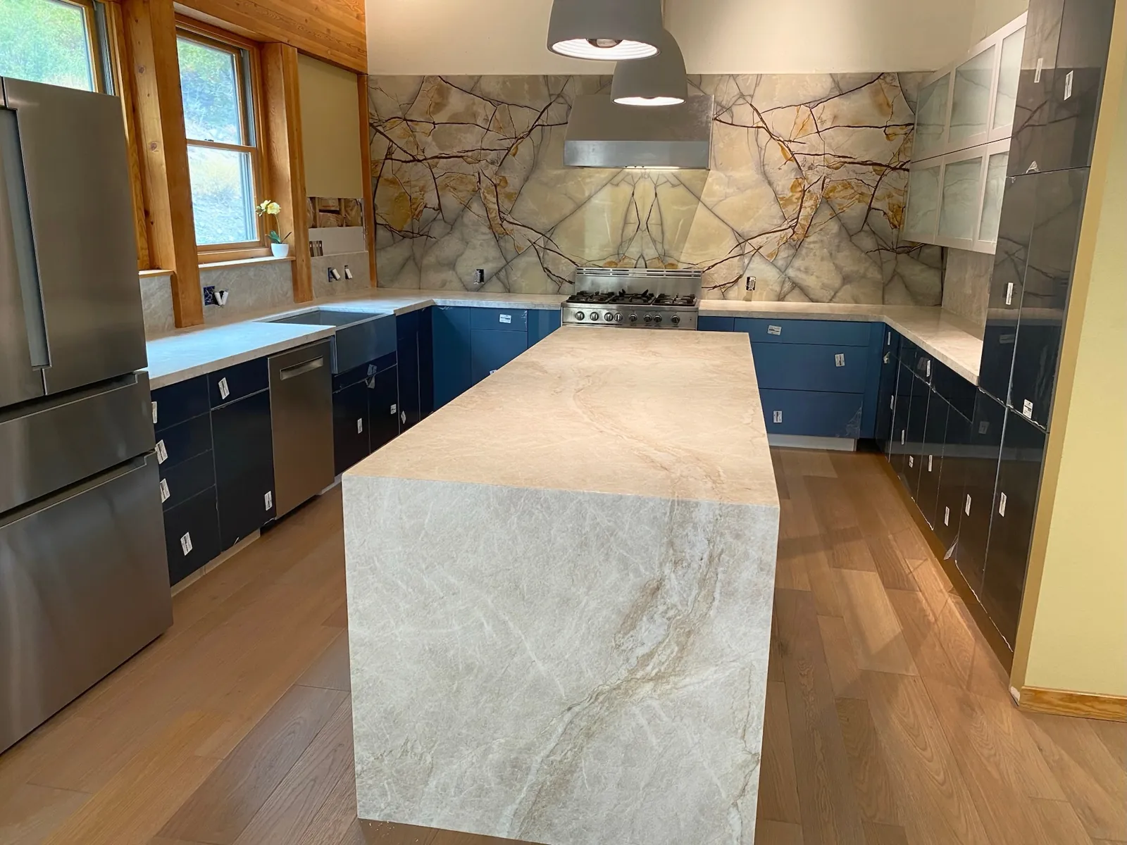 Leathered Taj Mahal quartzite waterfall island and book-matched quartzite slab backsplash in a Genoa, Nevada kitchen